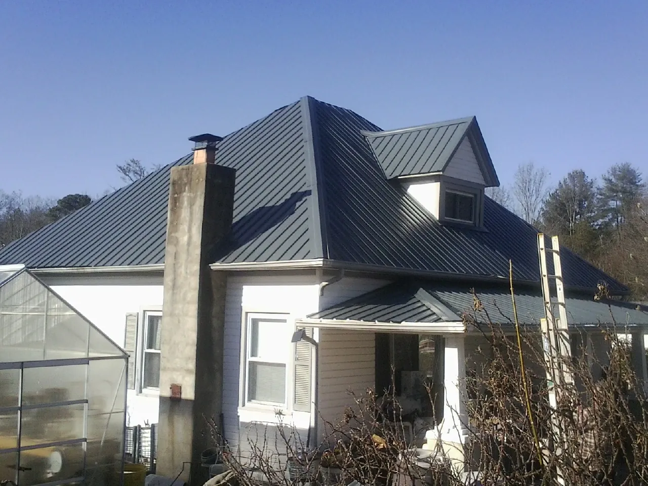 Dark blue standing seam metal roof on a white farmhouse with dormer — Slate & Tile Roof Repair by Roofing Brothers in New Paris