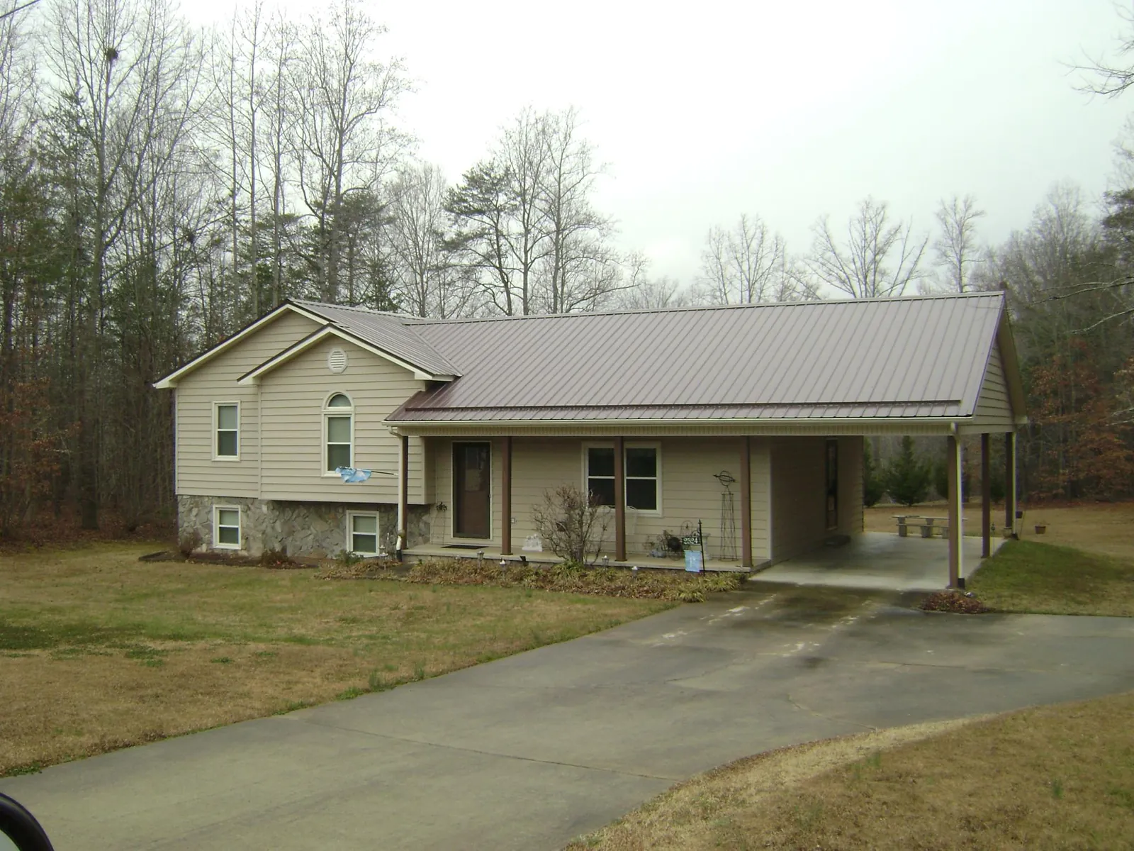 Brown metal roof on a tan split level home with an attached carport in New Paris